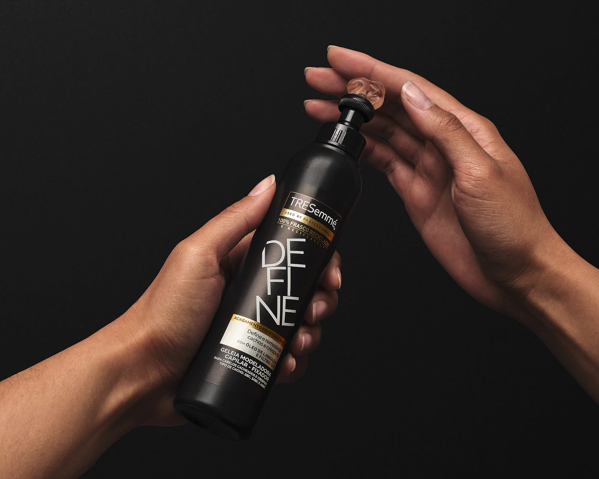 Two hands are reaching for a bottle in front of a dark background, suggesting a moment of interaction.