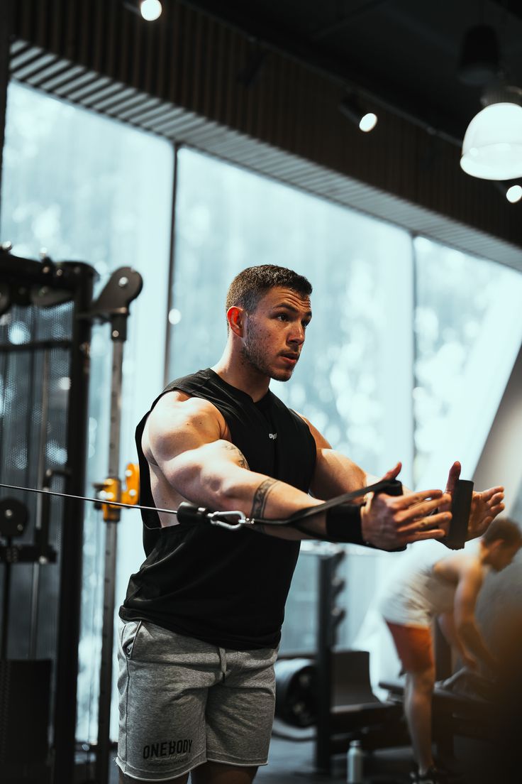 Muscular man pushes a weighted sled on green gym turf.