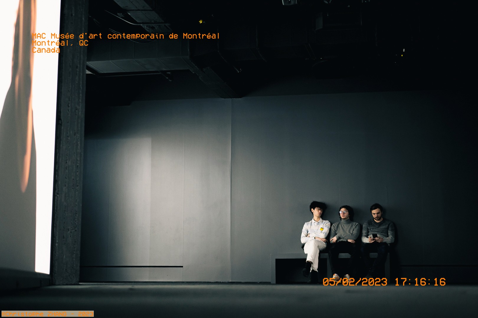 Trois visiteurs assis sur un banc au Musée d'art contemporain de Montréal.