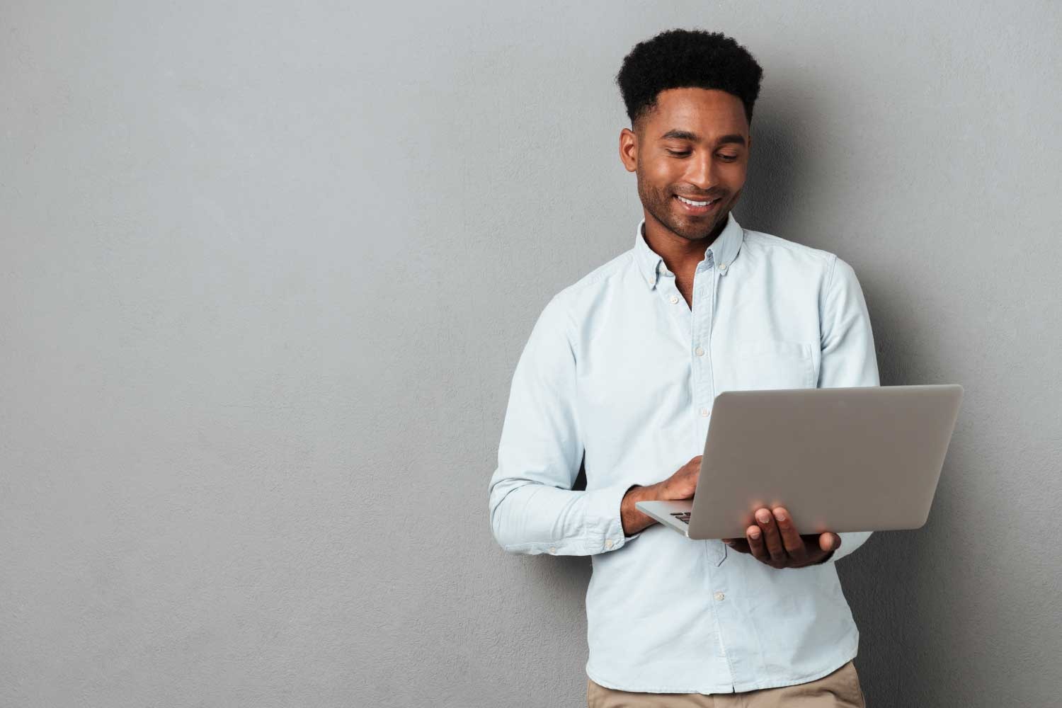 Profissional de tecnologia usando notebook em pé, representando mobilidade e praticidade no trabalho com TI - FindUP - Apresentação pessoal