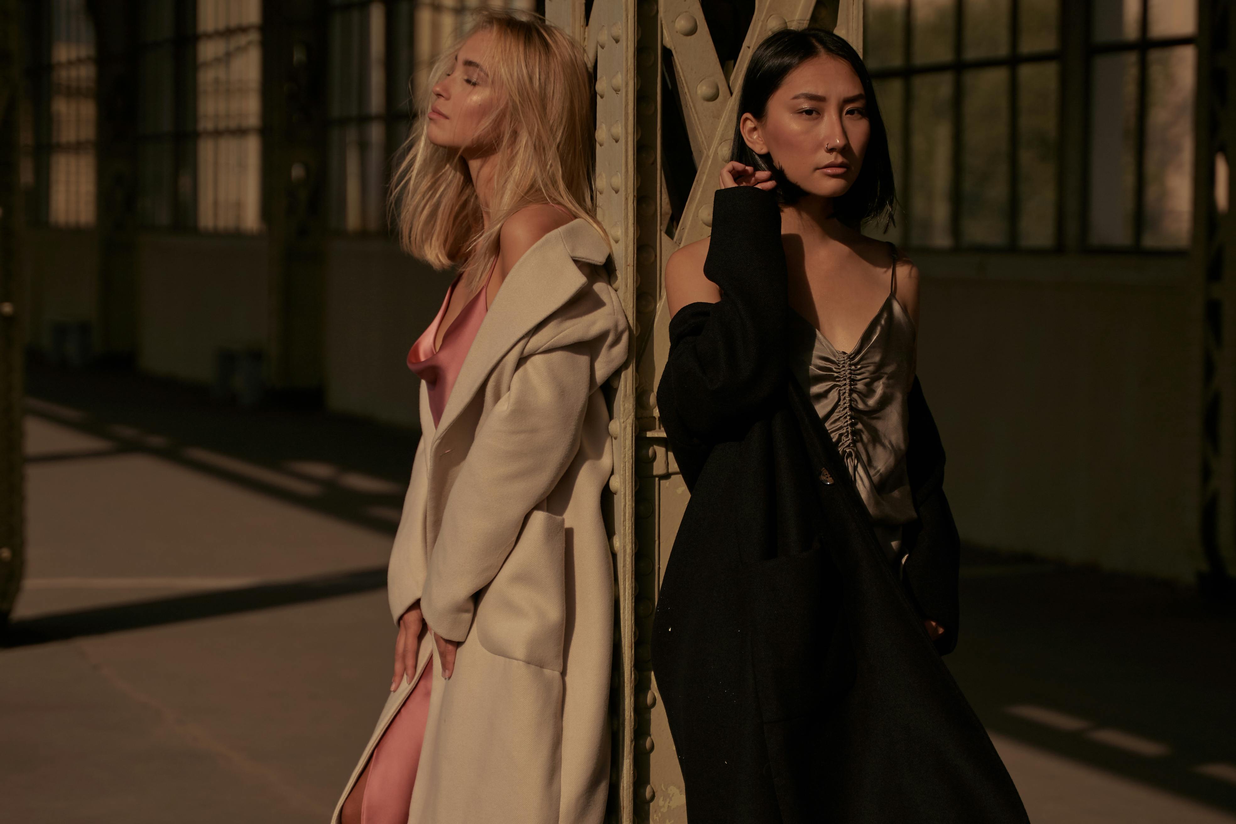 Two girls standing next to a metal pole