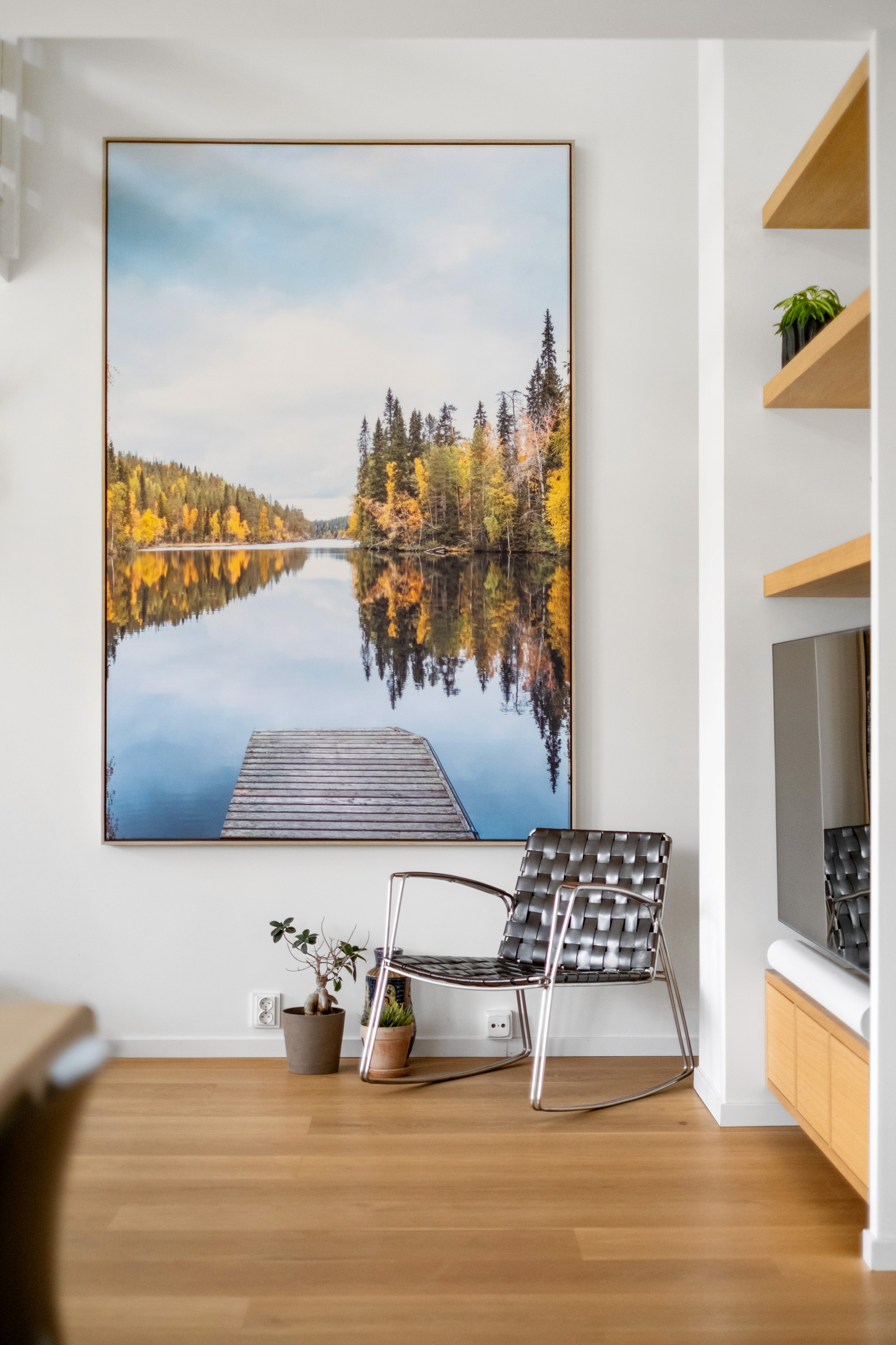 Interiør med stort landskapsmaleri og stol ved veggen
