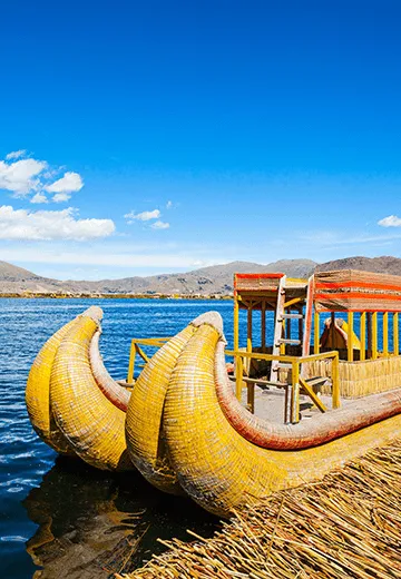 Embarcação tradicional de totora no Lago Titicaca, com estrutura artesanal flutuando sobre águas azuis no Peru