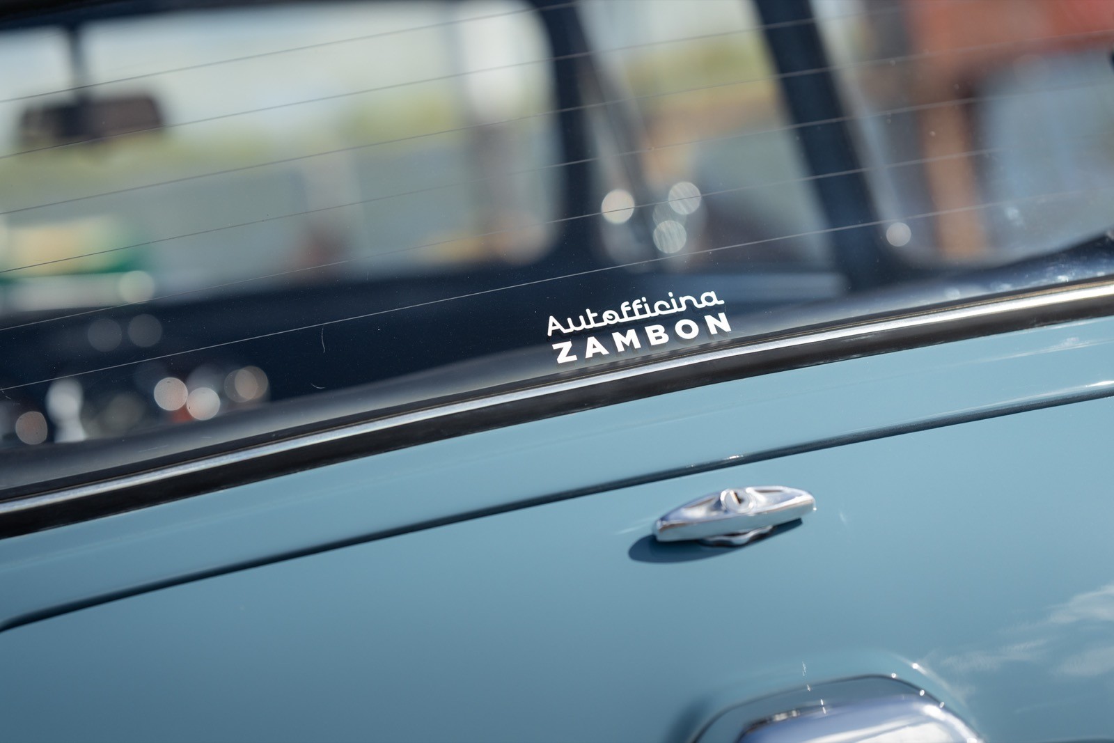 Close-up of a classic car's dashboard featuring emblem and controls against a blurred background.