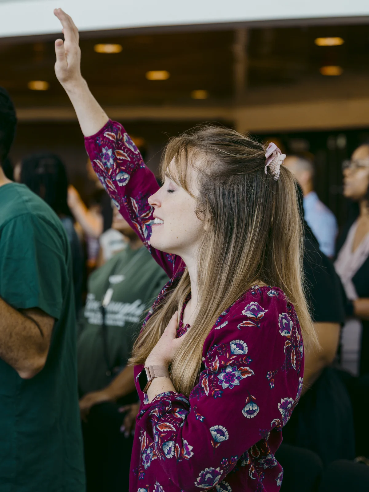 Woman with one hand raised and one on her heart during worship at Elan Church