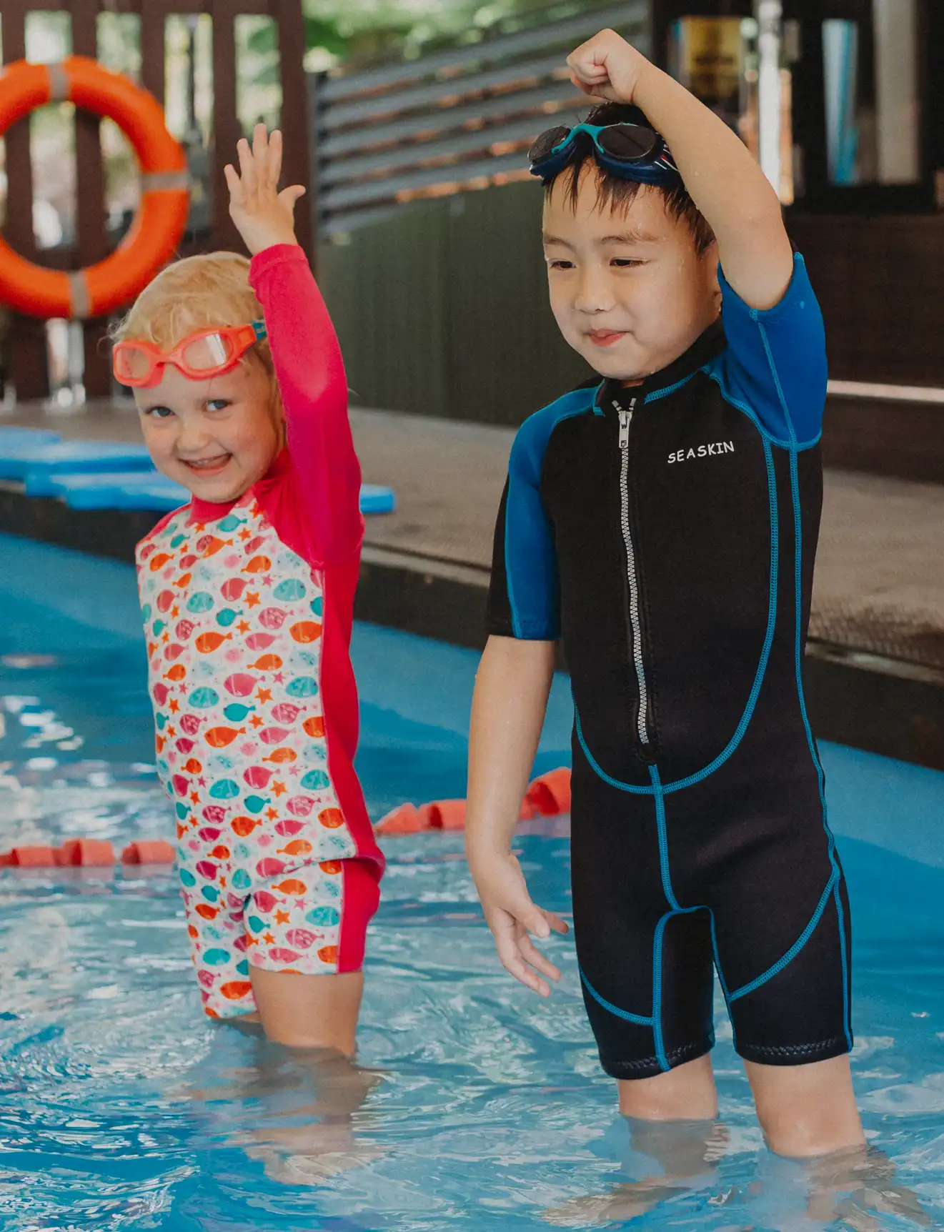 Children cheering with their arms up in the pool at a Swish holiday swim camp in Dempsey Hill, Singapore