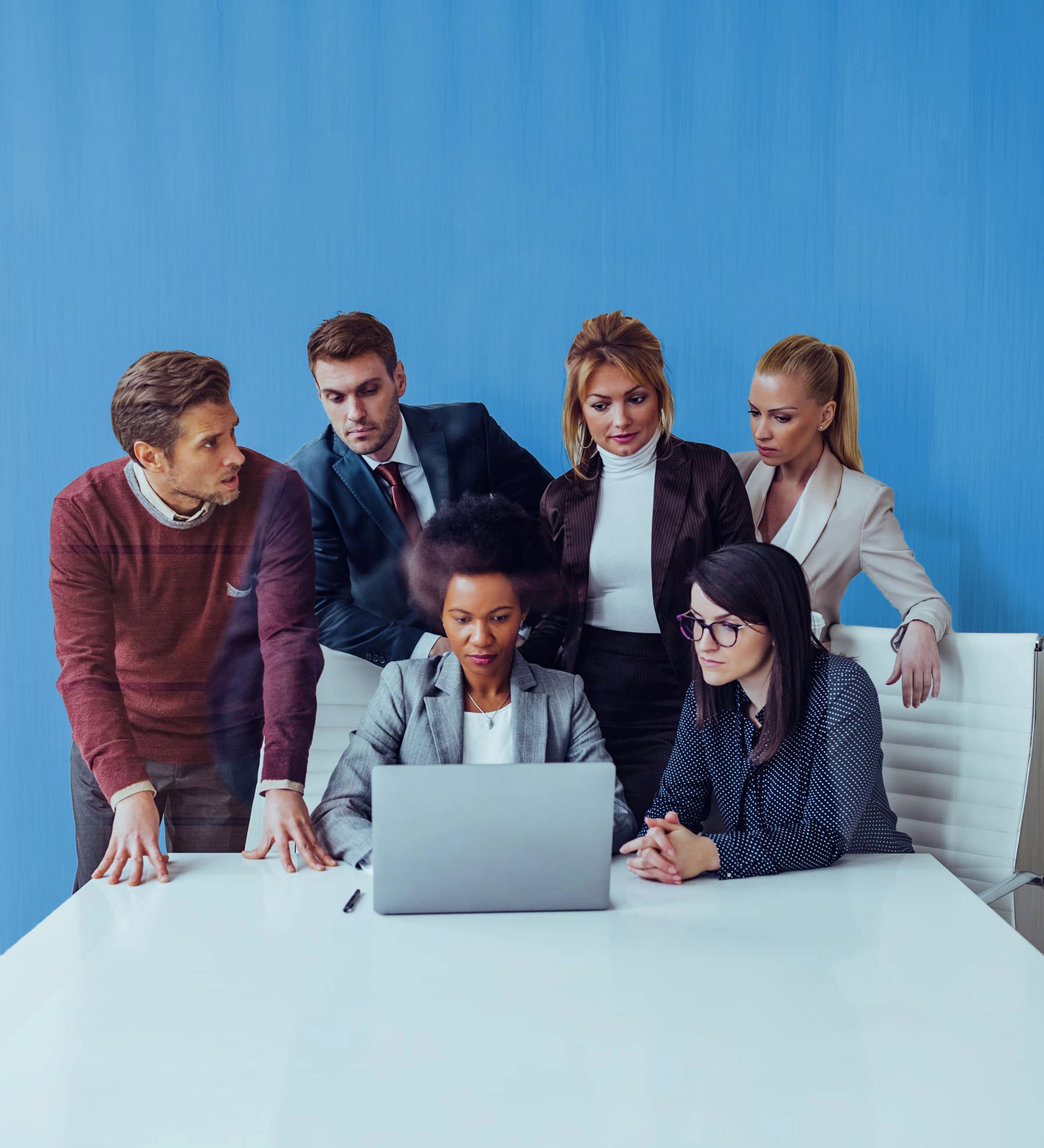 a group of colleagues looking at the laptop screen in the office