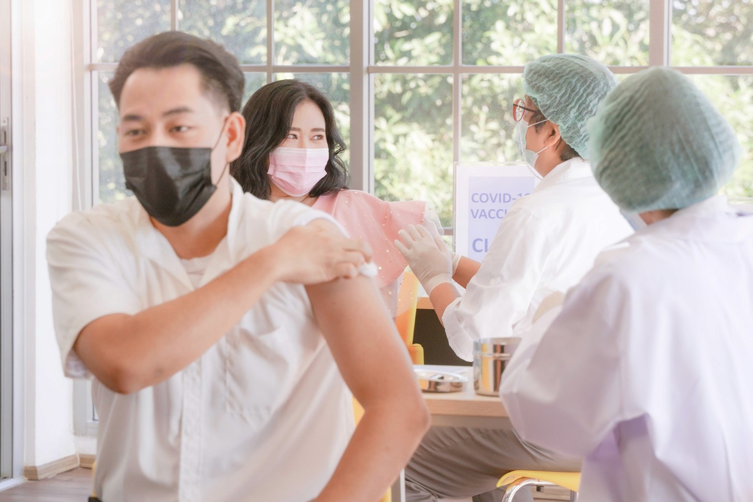 醫護人員為戴口罩員工接種疫苗，體現香港團體醫療保險及僱員福利保障。