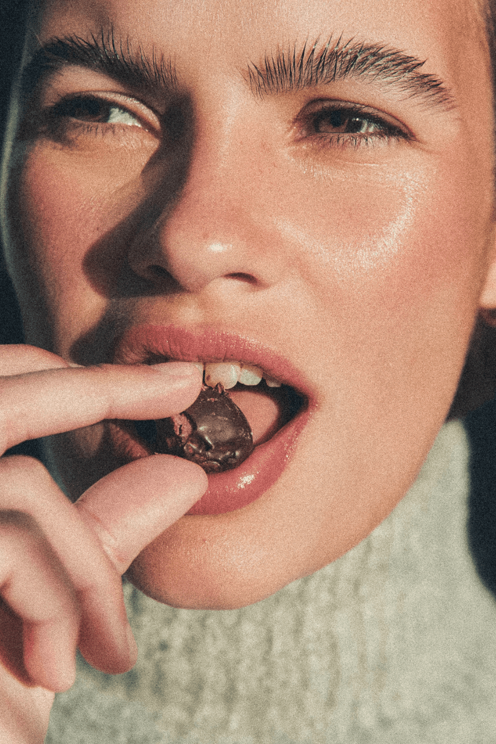 Person in a dark shirton a phone call, seated at a desk with papers, exudes a thoughtful, focused demeanor. Background shows dark horizontal blinds.
