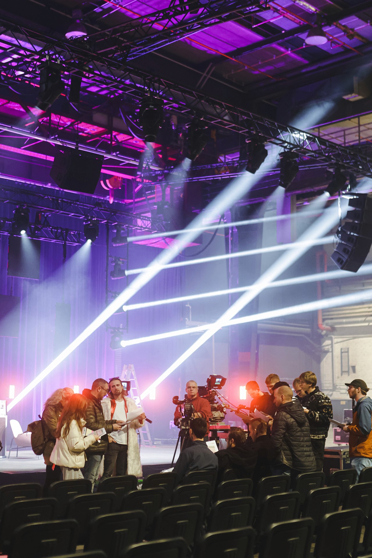 A large group photo of diverse team members gathered in an industrial-style space with arched ceiling.