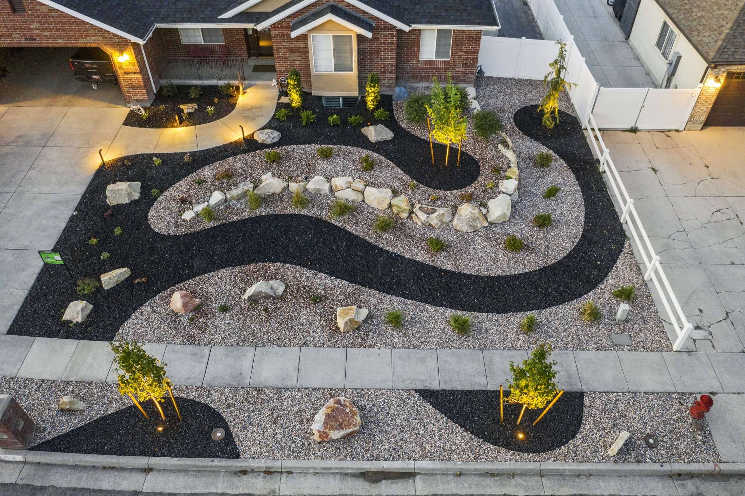 Riverton Residence xeriscape front yard with dual-tone gravel beds and accent boulders