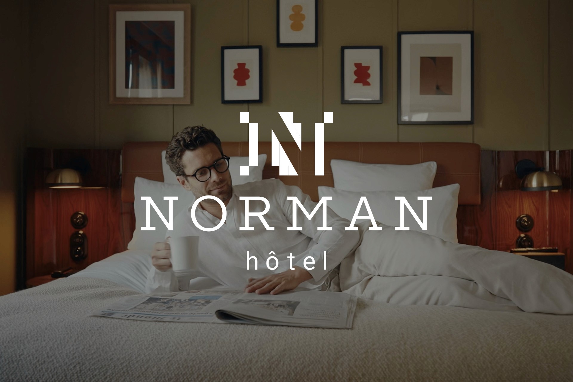 Man laying on a bed. Whote logo Norman 