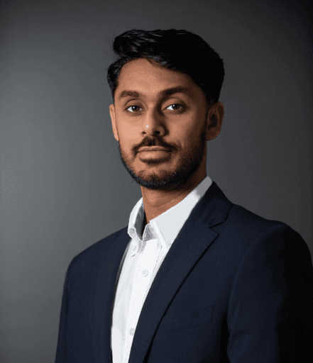 Person wearing a suit and white shirt, posing for a portrait against a dark gray background.