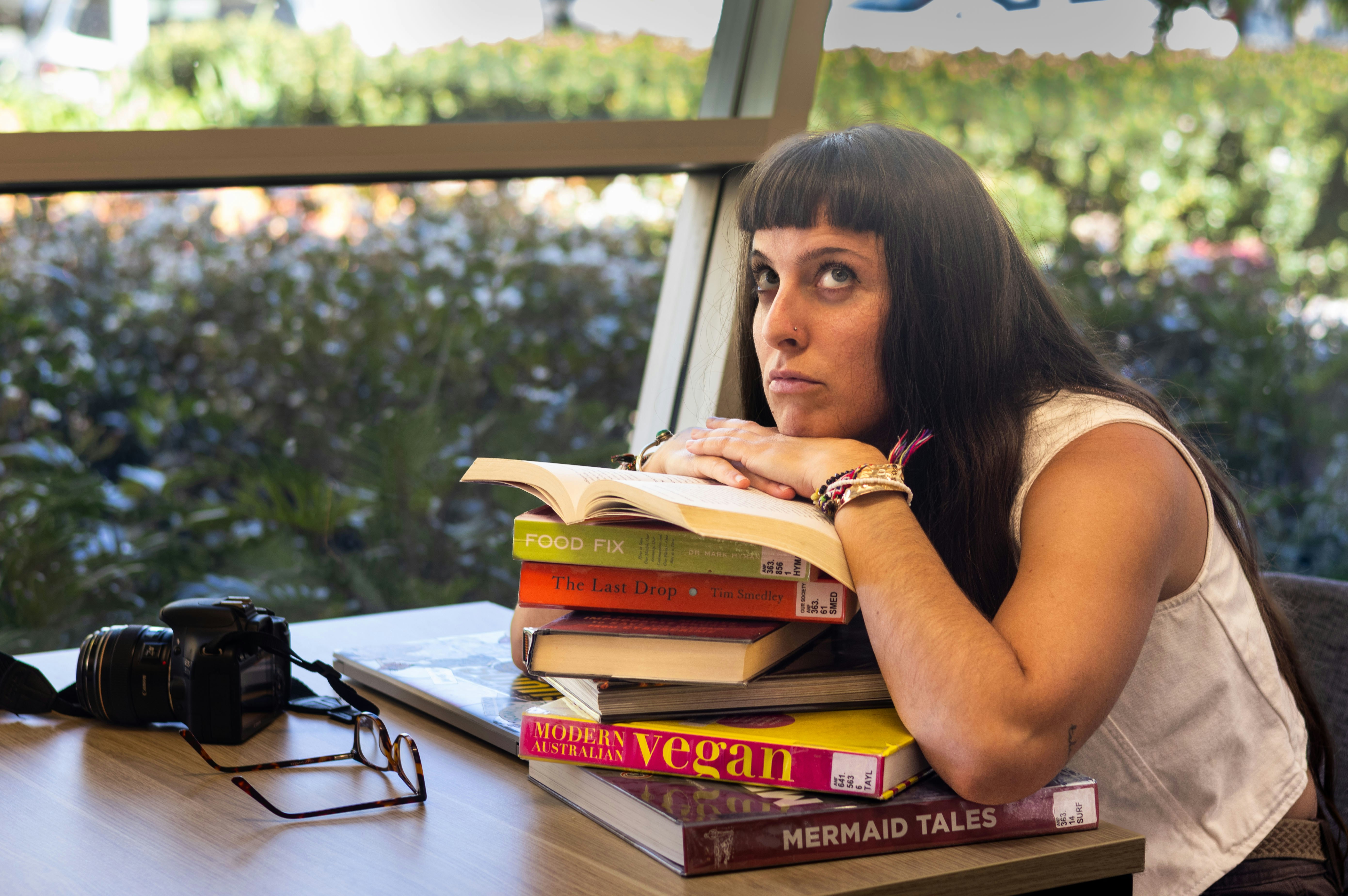 Woman resting her head on a stack of books.