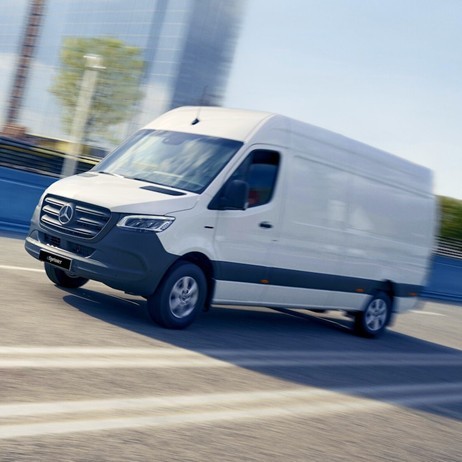 a white van driving down a street next to tall buildings