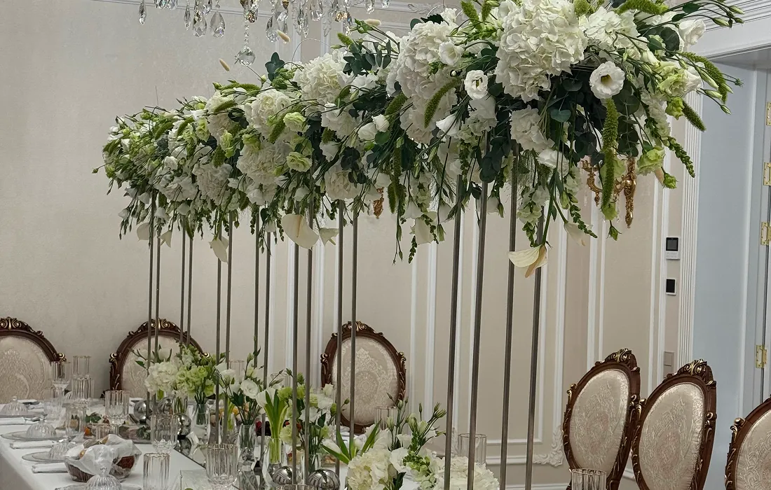 Elegant white hydrangea and eustoma floral arrangement on tall glass vases for a home wedding table decoration