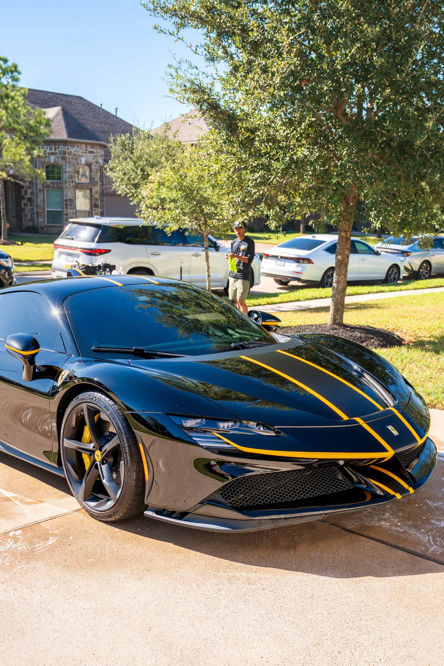 Mobile car detailing in Houston featuring a black Ferrari with yellow racing stripes parked on a residential driveway.