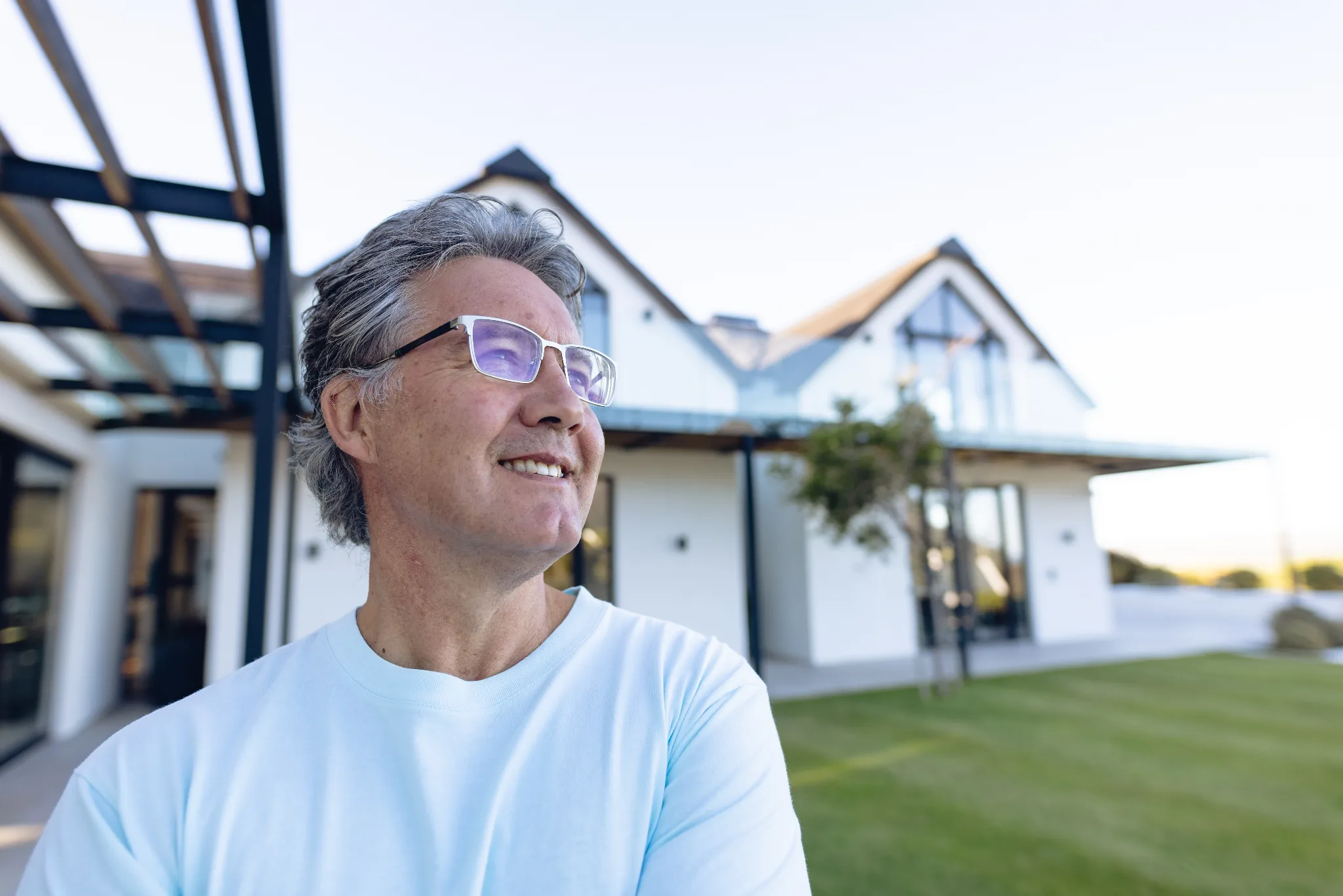 Middle-aged man smiling with a out of focus house in the background