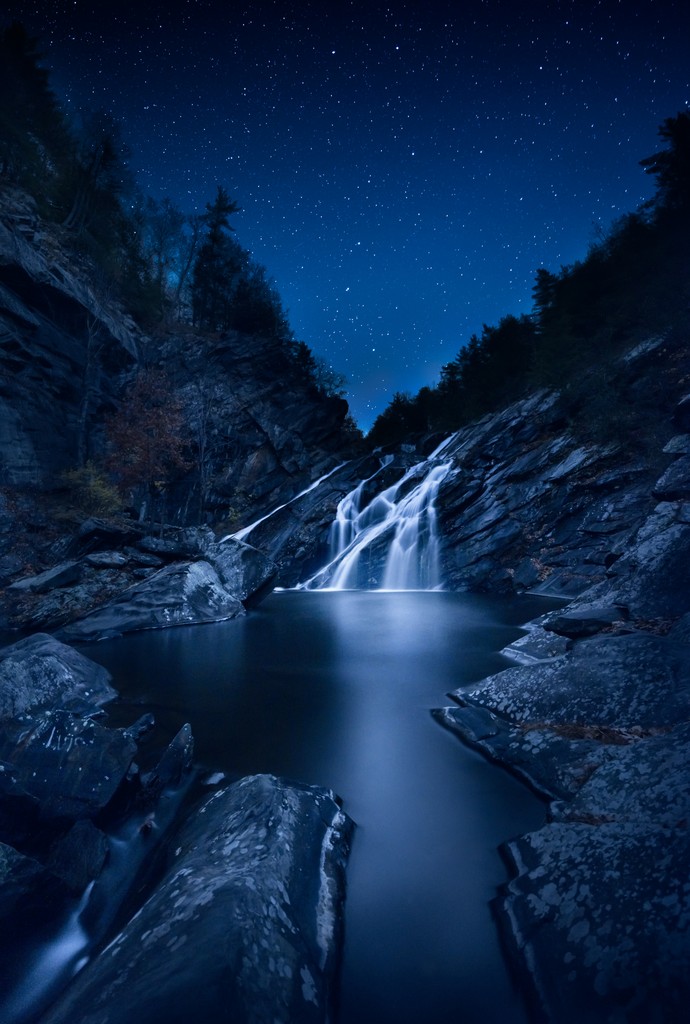 A waterfall on a clear night with stars in the sky