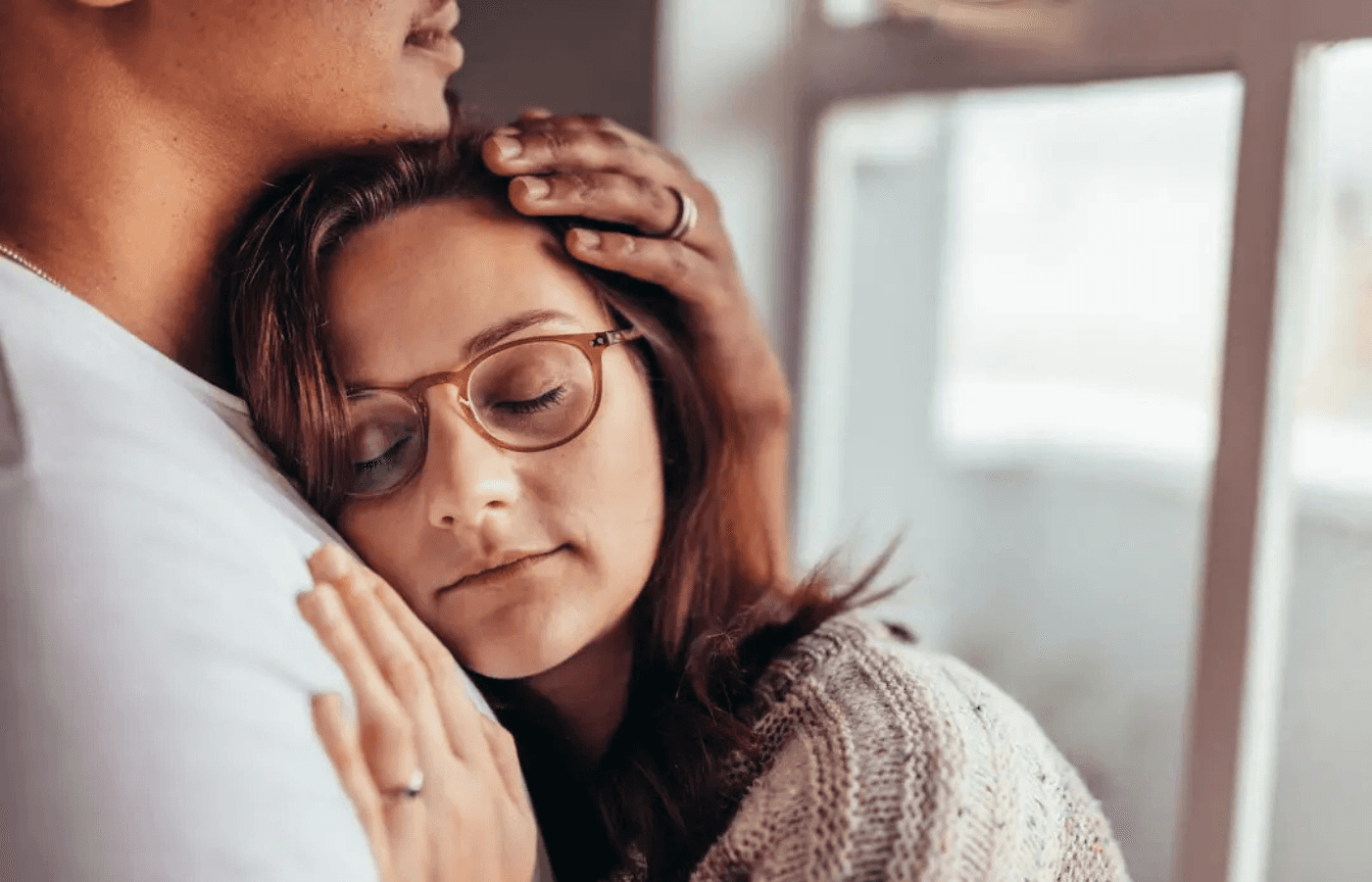 woman leaning on man's chest with eyes closed