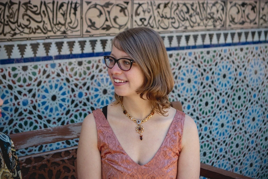 Woman with glasses smiling and looking to the left.