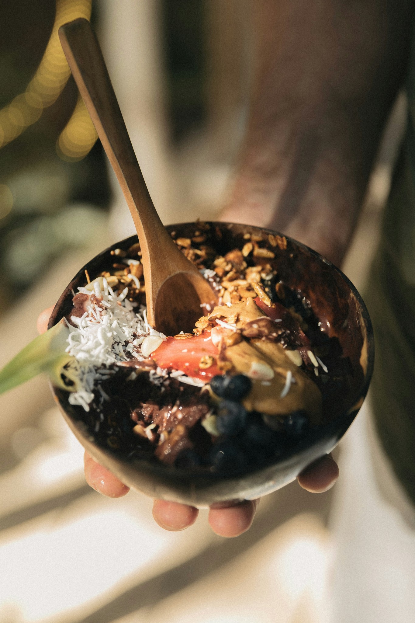 açaí bowl held in somone's hand with a spoon sticking out