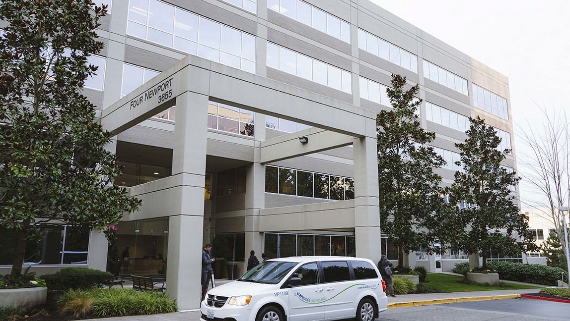 A white van is stationed before a bland, five-story beige corporate building, underscoring the unremarkable T-Mobile architecture.