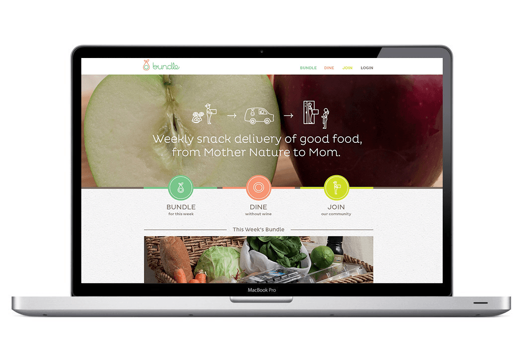 A laptop screen displays the Bundle website, featuring a clean design with a light gray background and white text. The header reads “Bundle” with a logo next to it. The central message reads “Weekly snack delivery of good food, from Mother Nature to Mom.” Three circular icons are shown: “Bundle for this week,” “Dine without wine,” and “Join our community.” Below these icons, a basket of fresh produce is depicted, including carrots, lettuce, and a green bell pepper. The bottom of the screen shows “This Week’s Bundle” and a MacBook Pro logo. The laptop is positioned horizontally against a white background.