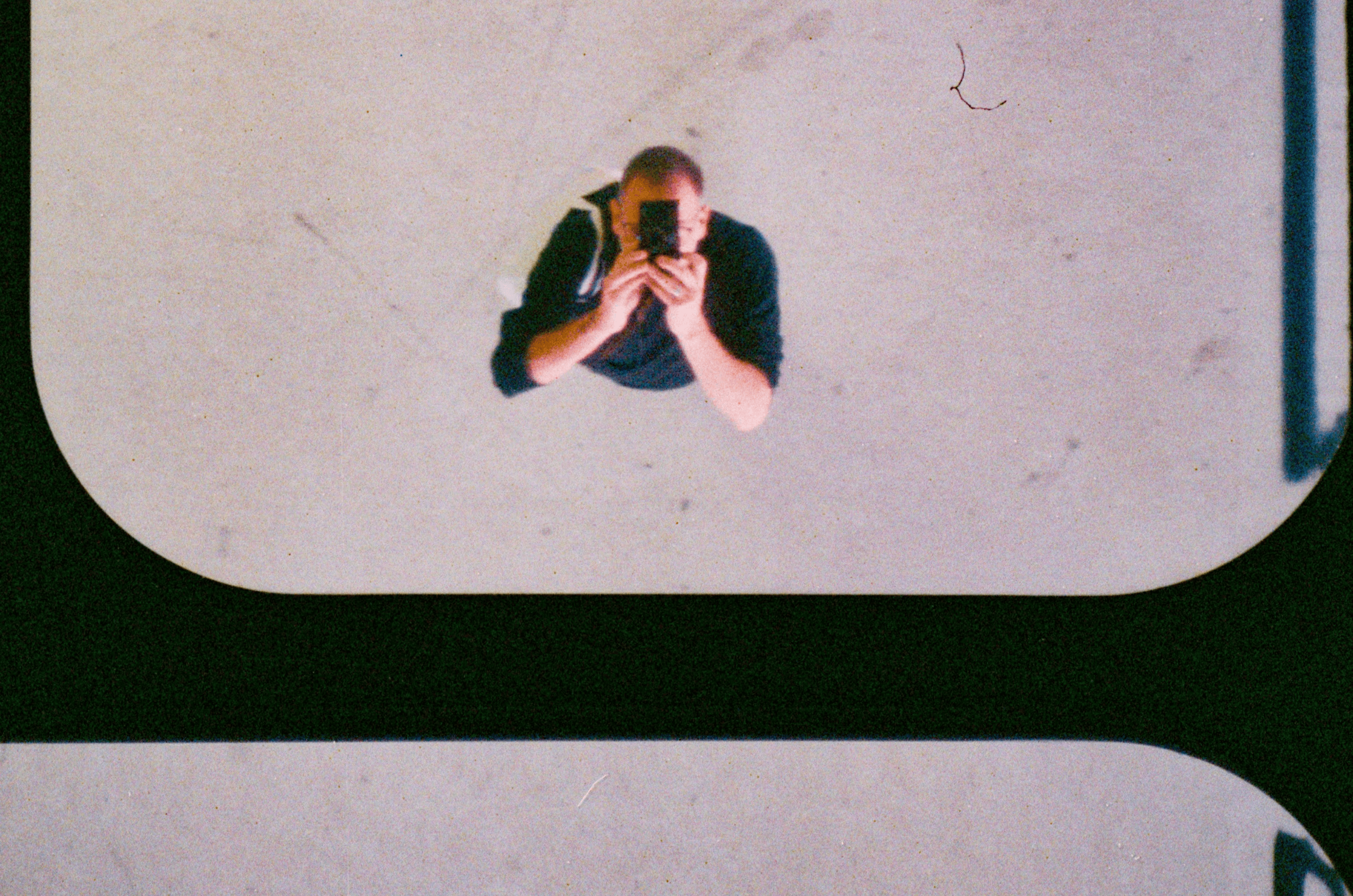 Overhead view of a person taking a photo with a smartphone, seen from above against a minimal background — reflecting data-driven visibility, analytics clarity, and syncing LinkedIn Ads insights into HubSpot for B2B SaaS growth.