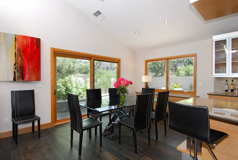 Bright dining room with large windows, dark floors, and colorful artwork. Photo by Chris Darnall for Irvine Transitional Modern Project. Photo by Chris Darnall.