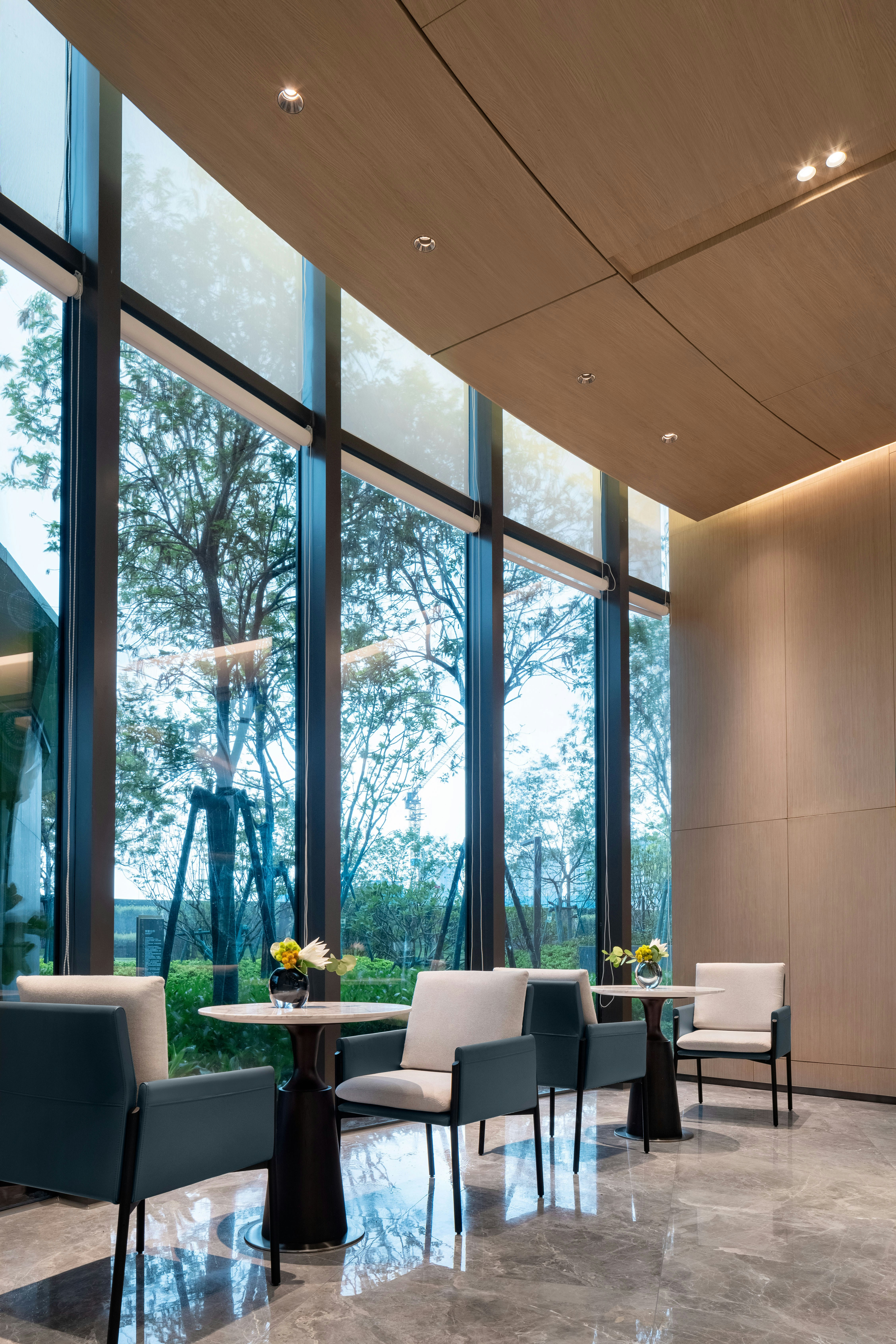 Modern seating area with large windows and trees outside.