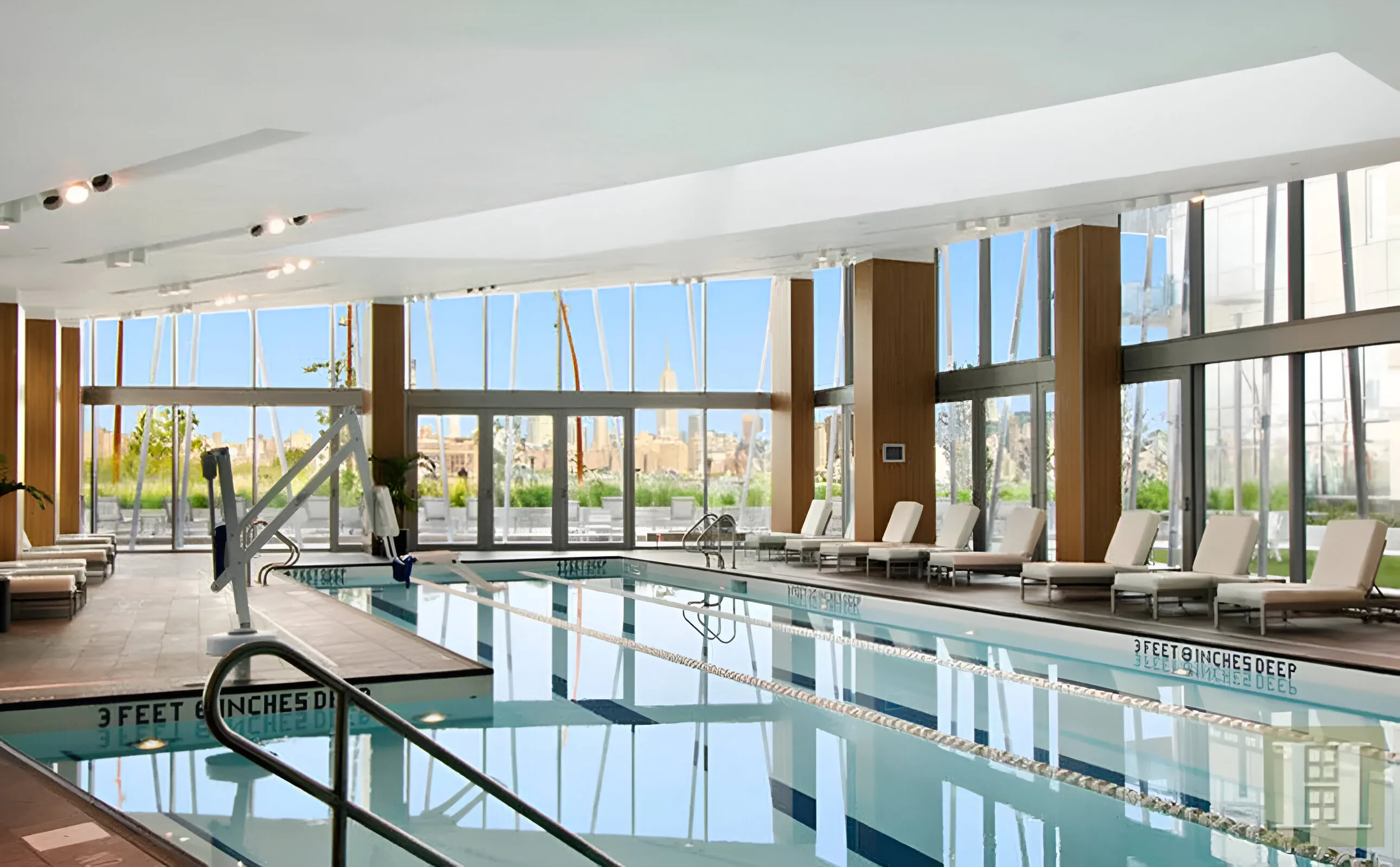 Indoor swimming pool with a panoramic view of the city skyline through large windows.
