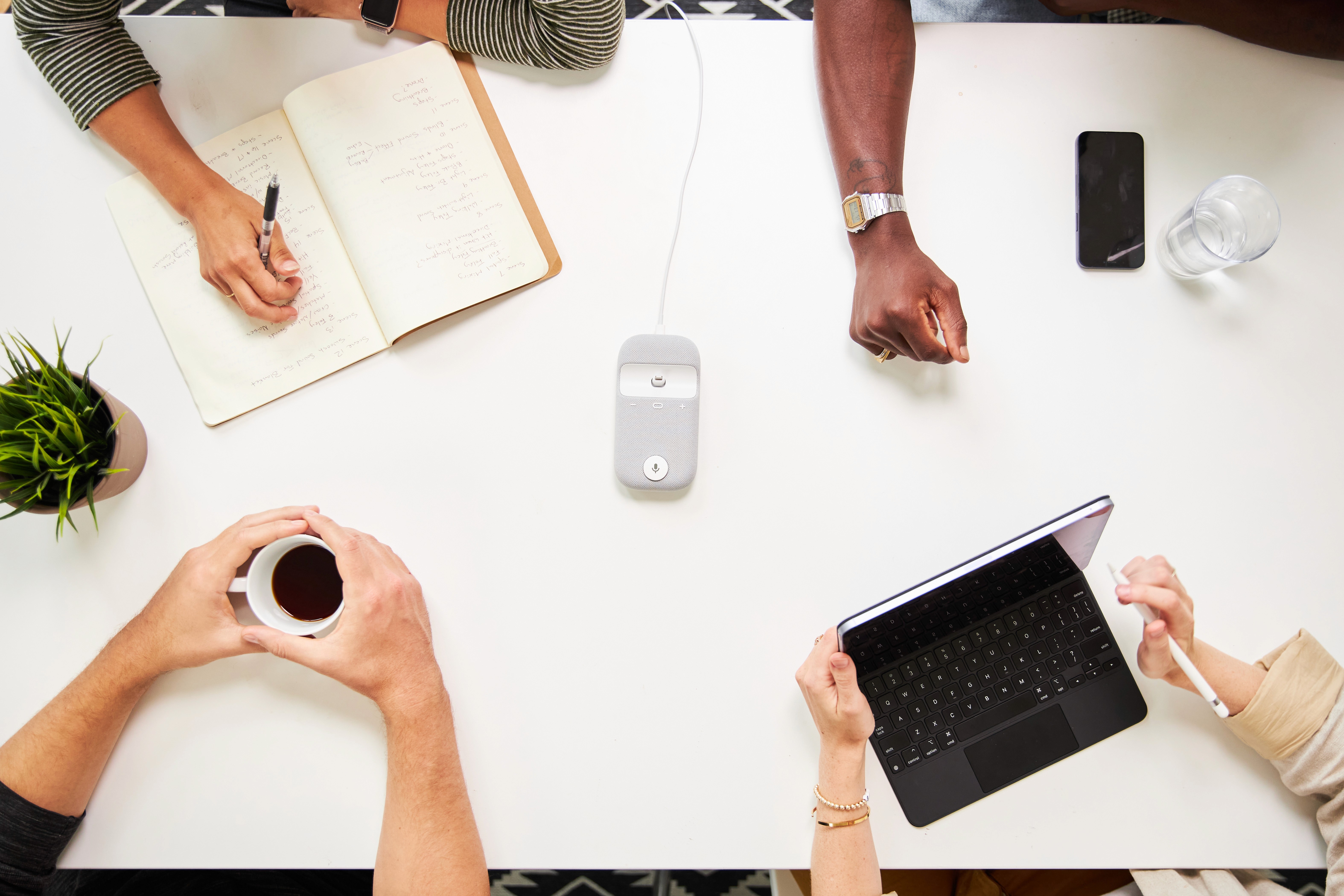 top-down view of office table with workers arms and notebooks on the table