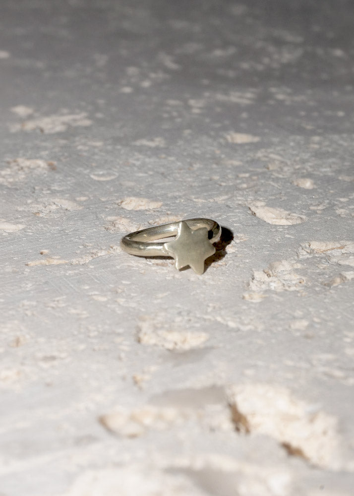 Silver ring with a unique star design on a textured surface
