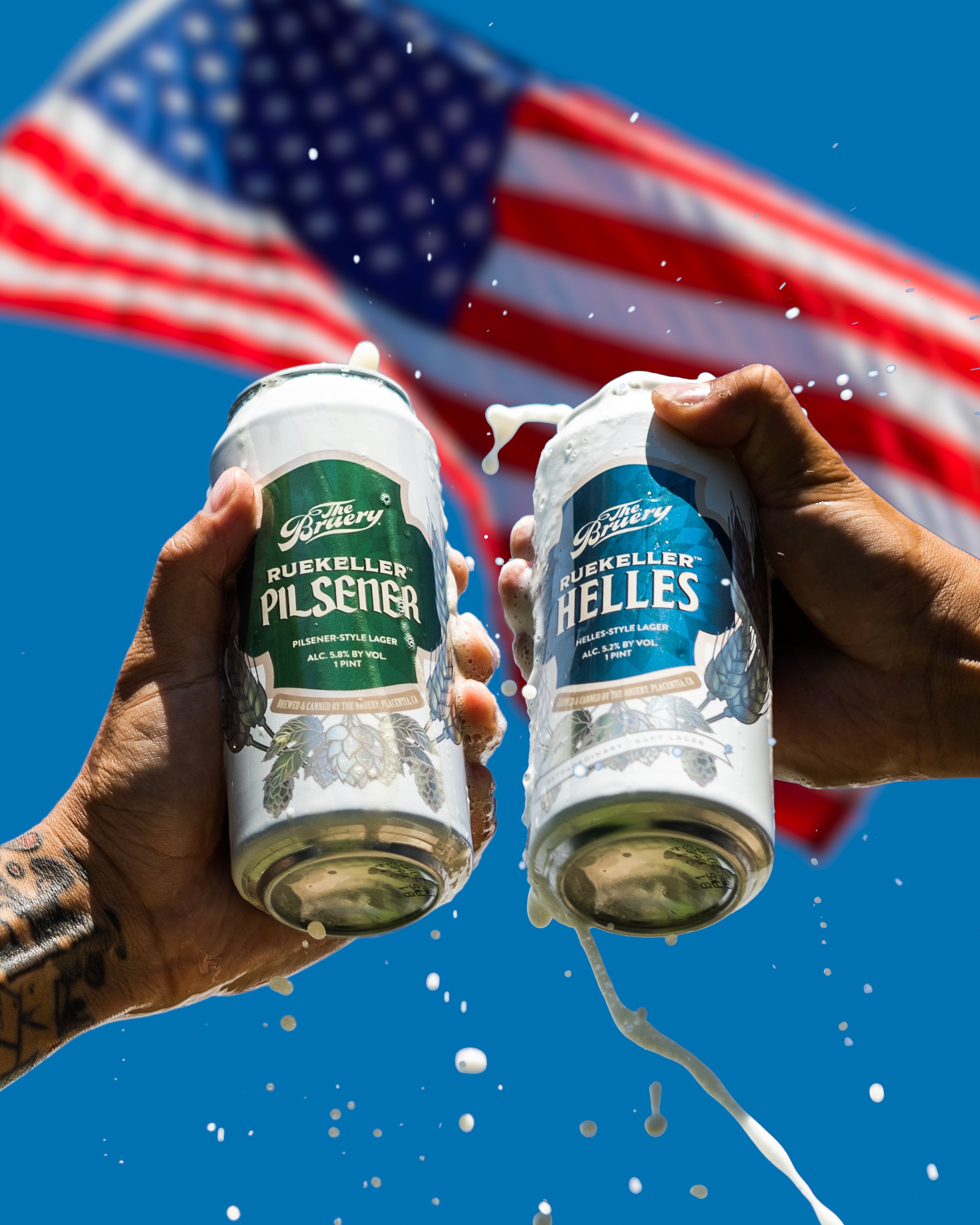 Hands holding The Bruery pilsner and helles cans