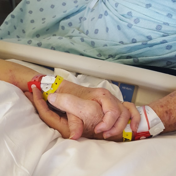 Two people holding hands in a supportive care moment.