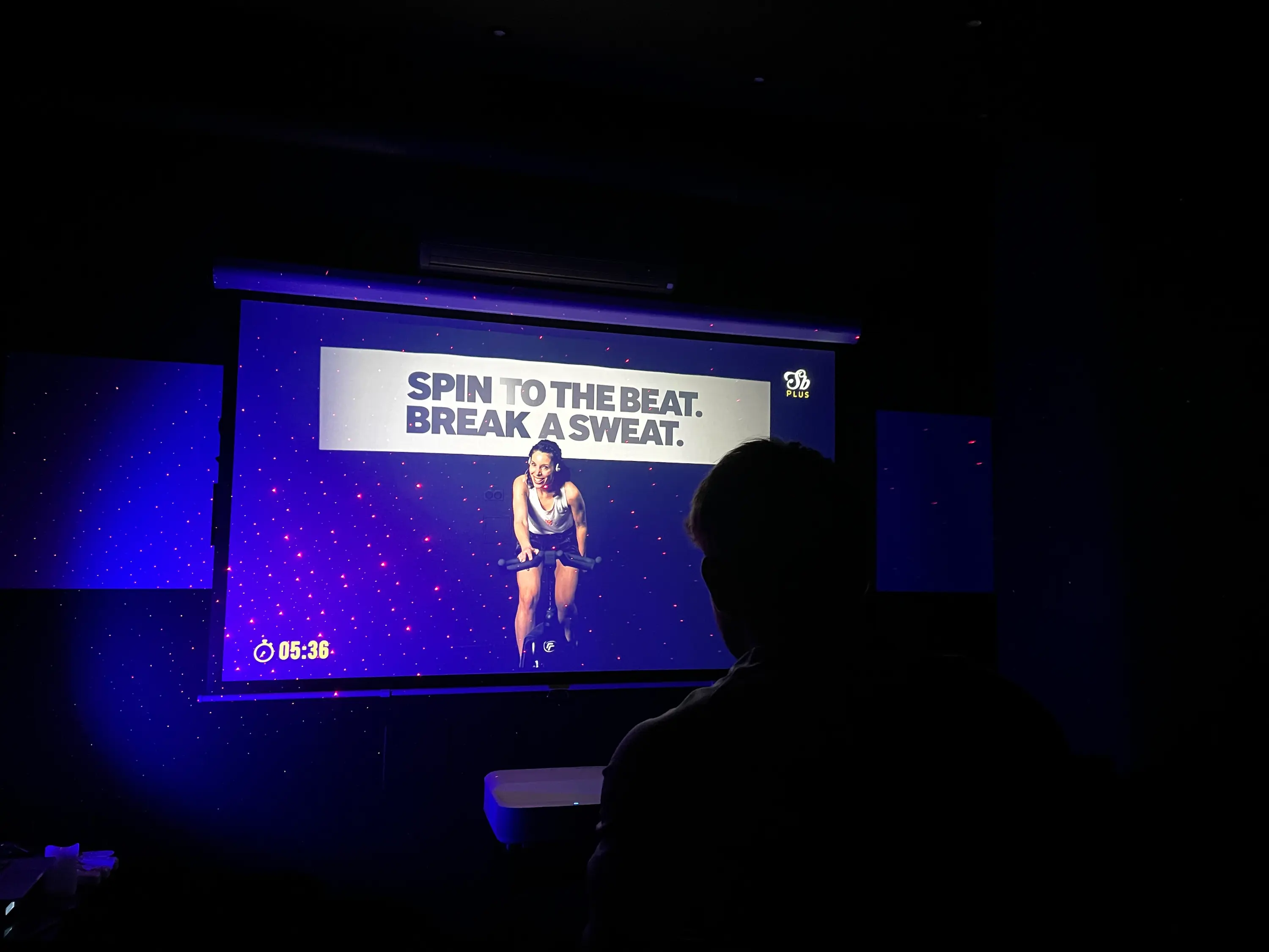 Participant regardant un cours de cycling en vidéo dans la salle VOD de Spinbreak Bordeaux