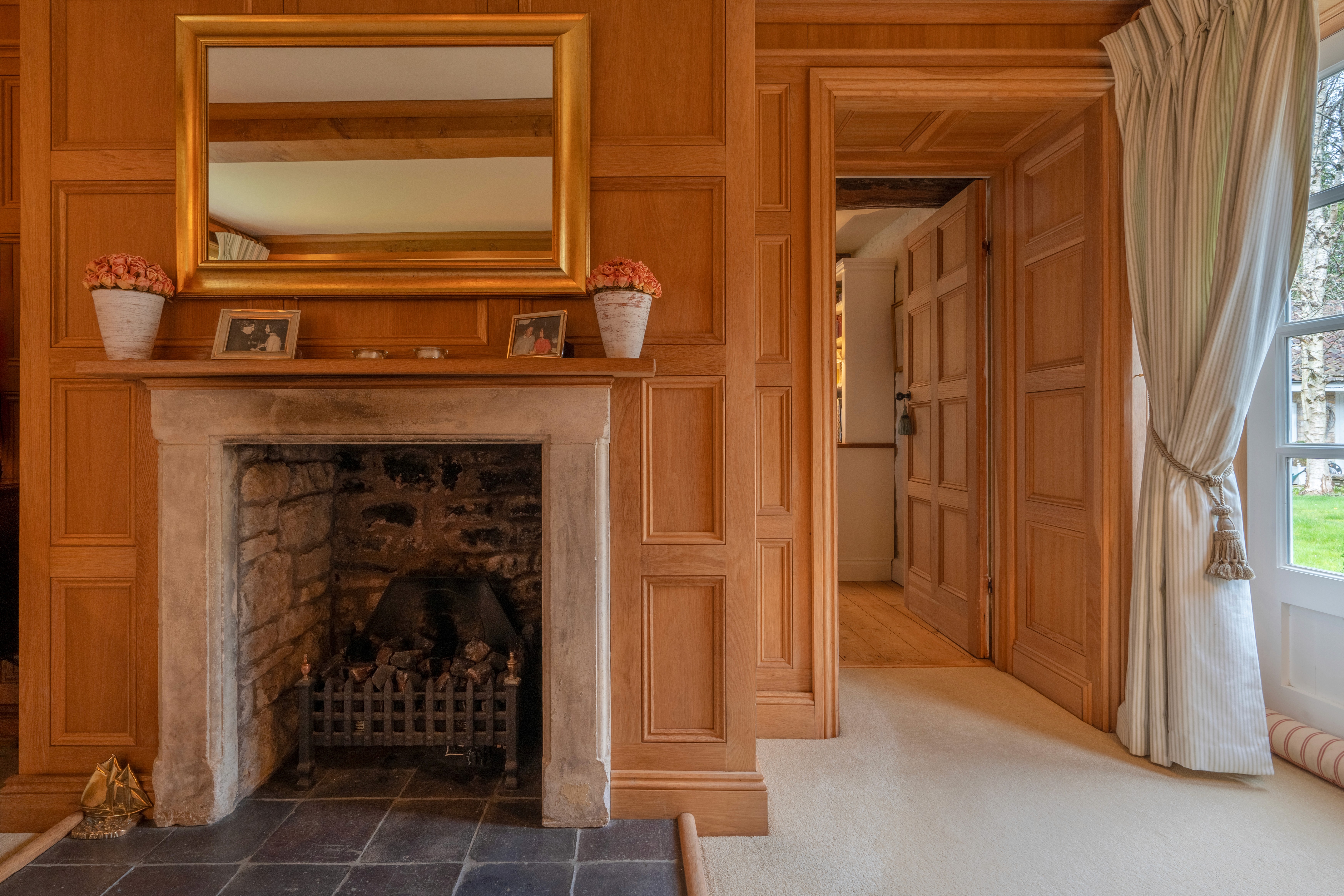 Stone fireplace surrounded by bespoke timber panelling
