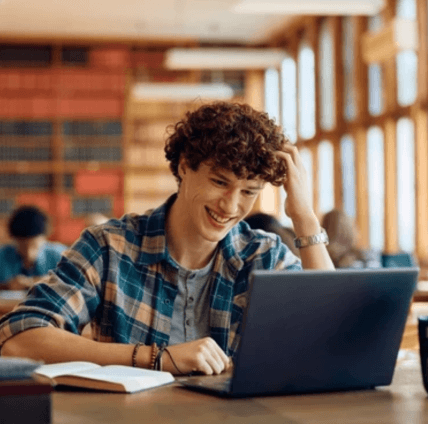 Boy studying in the library on his laptop