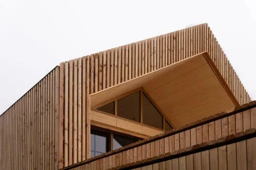 Dachaufbau aus Holzlatten mit eingeschnittener Fensterloggia vor weißem Himmel