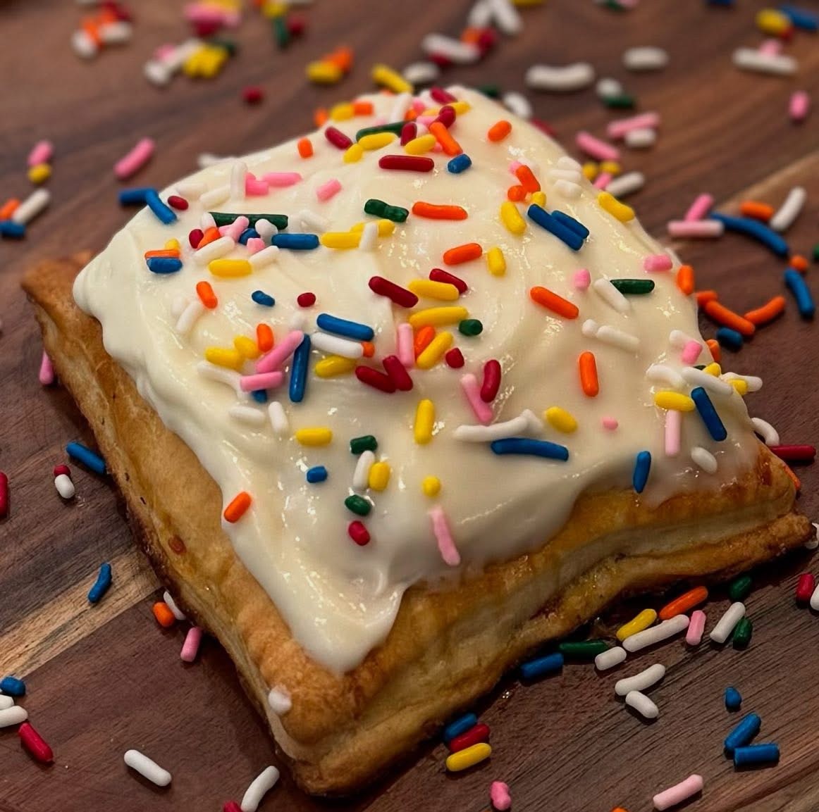 sourdough pop-tart with frosting and sprinkles on a wooden countertop