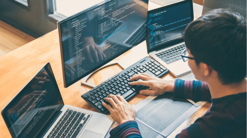 A person works on computer with multiple monitors.