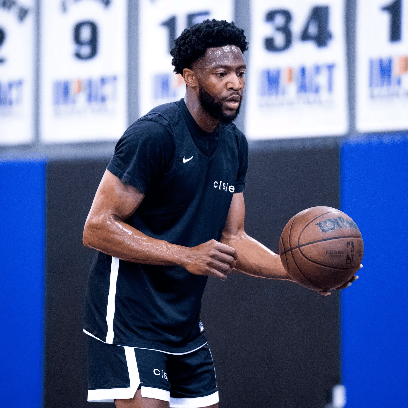A basketball player preparing to shoot a freethrow. Retired numbers hang in the background. 
