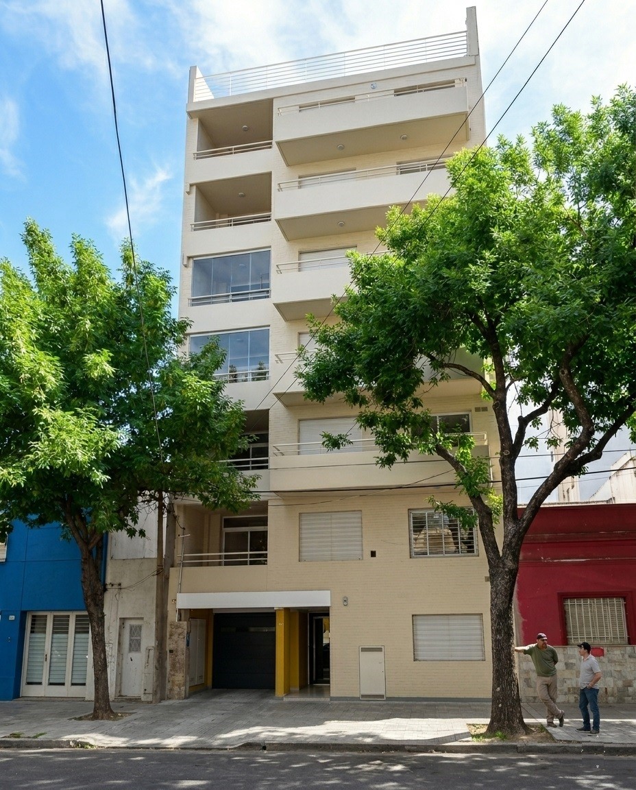 Frente de edificio de departamentos con revestimiento beige, balcones escalonados, terraza superior y cochera en planta baja, Cerrito 1326, Rosario