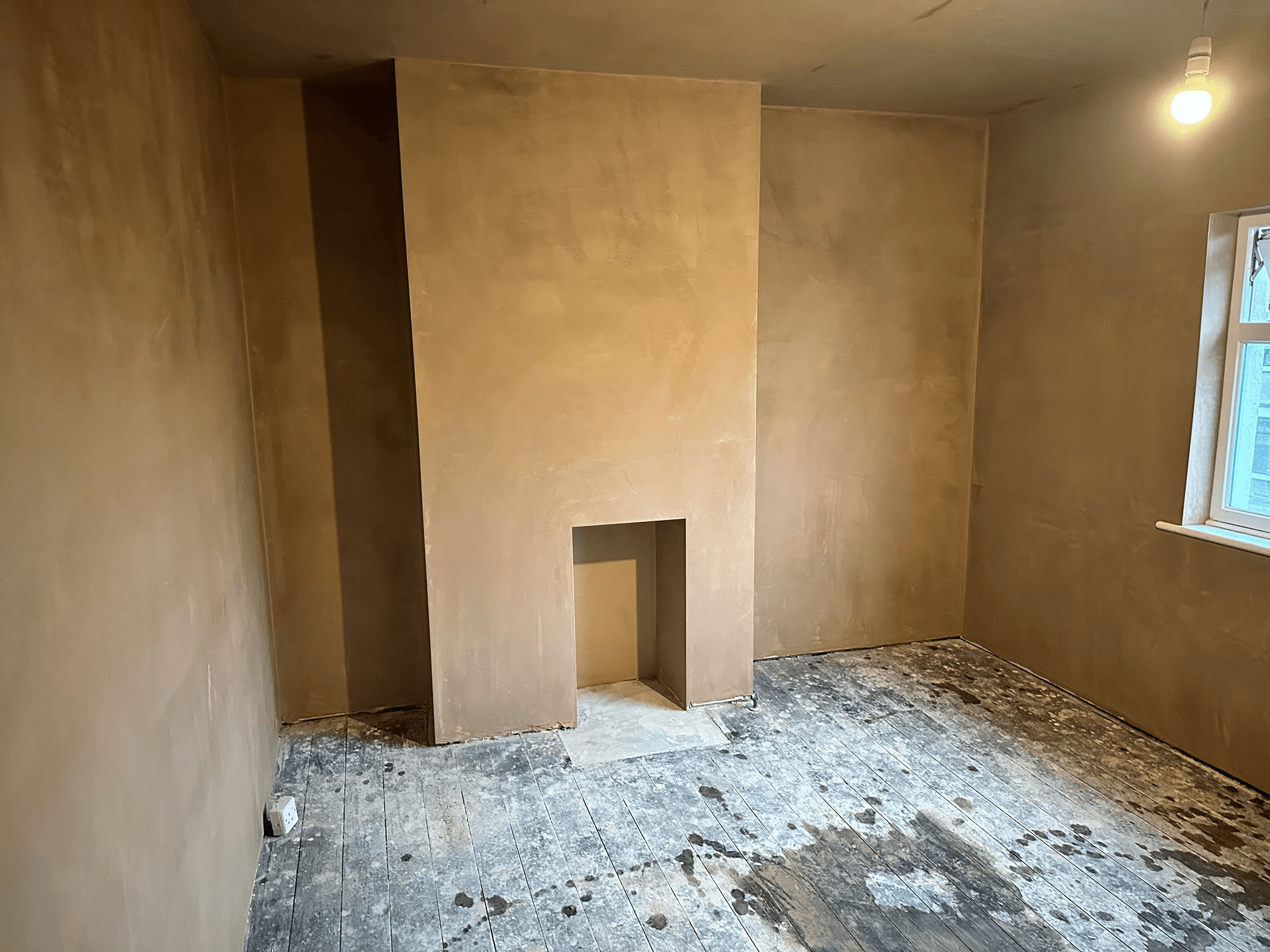 Freshly plastered chimney breast wall with fireplace.
