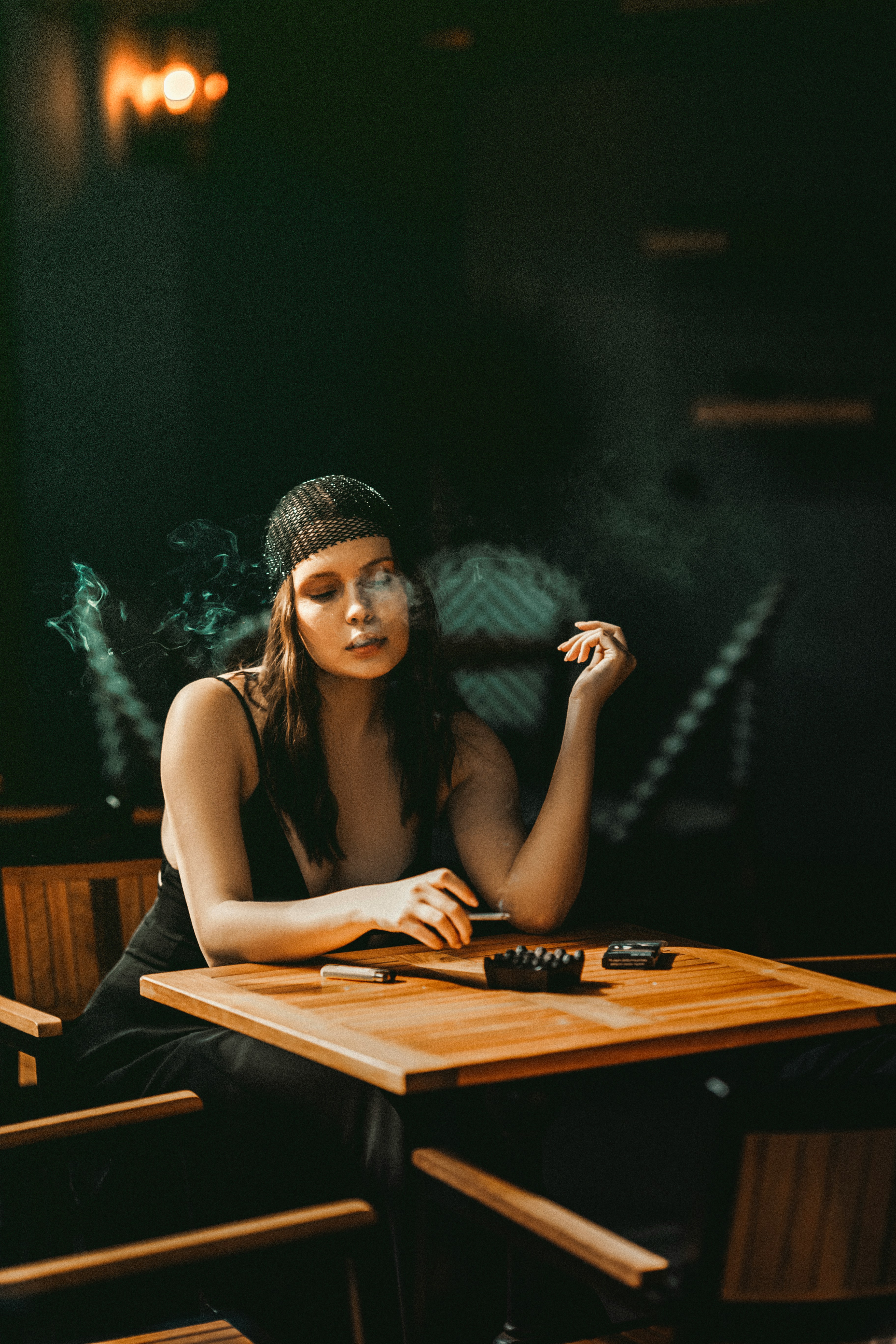 a woman sitting at a table smoking a cigarette