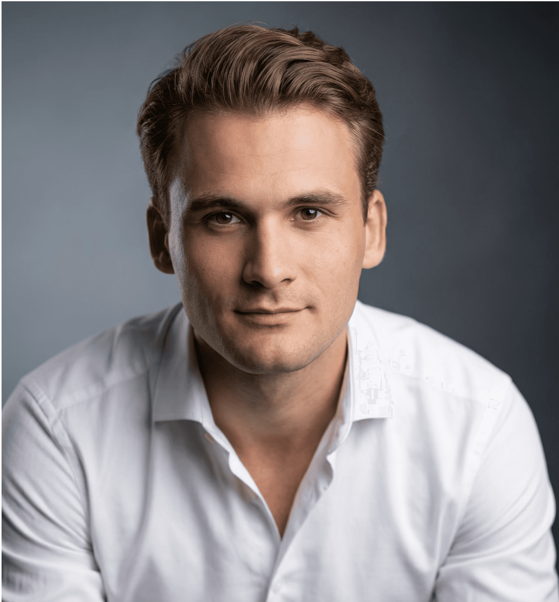 A smiling man with short hair stands with arms crossed, wearing a dark shirt against a neutral background.