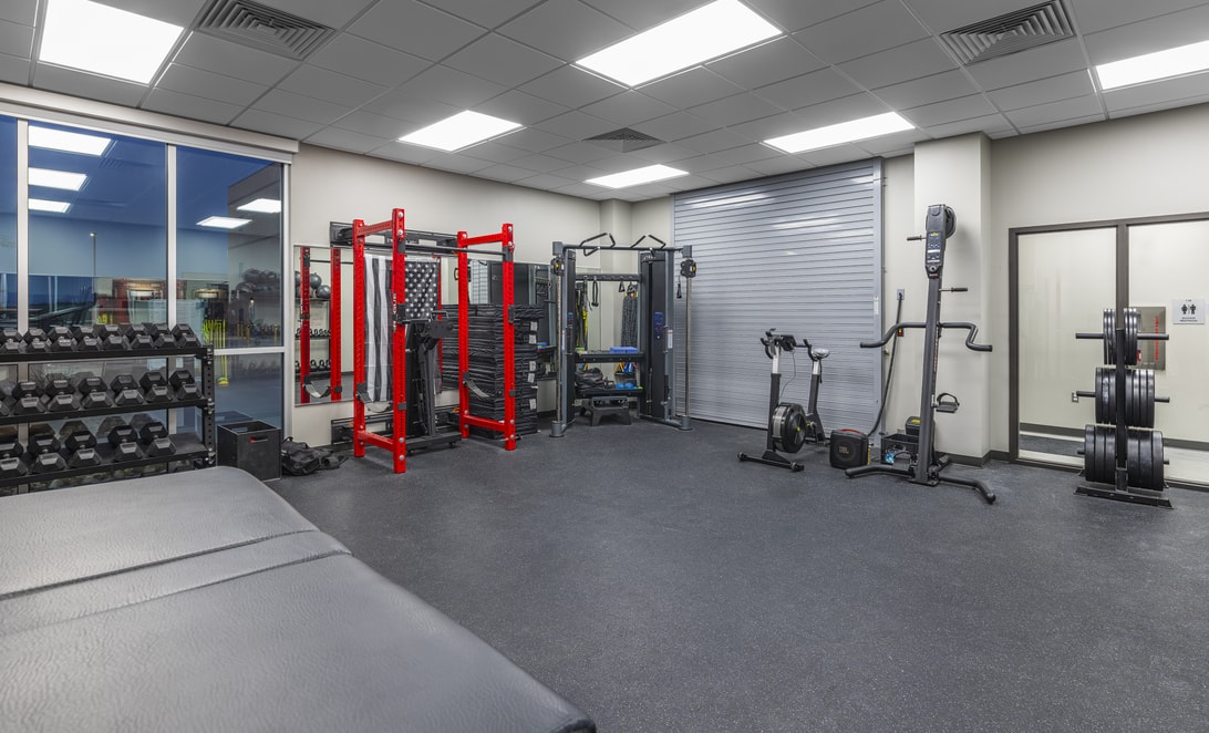 Fitness room with a training rig, weight machines, and cardio equipment at Travis County ESD 2 Pflugerville Fire Training Facility, by Martinez Architects