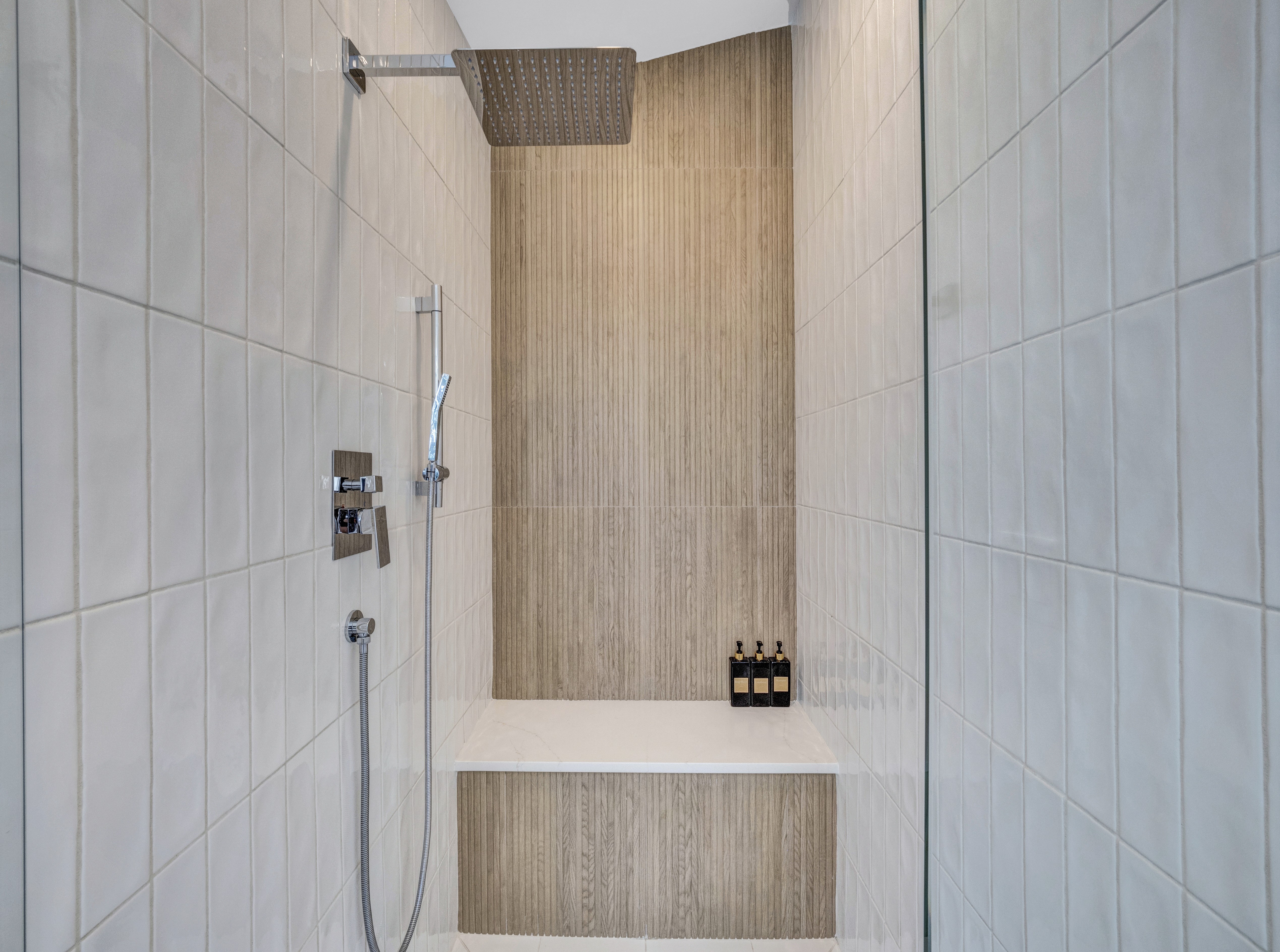 Interior of a luxury shower featuring a marble bench and vertical wood-slat accent tiles