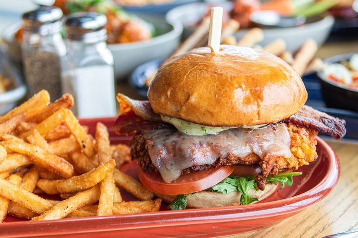 a chicken, bacon, and ranch sandwhich on a burger bun with fries